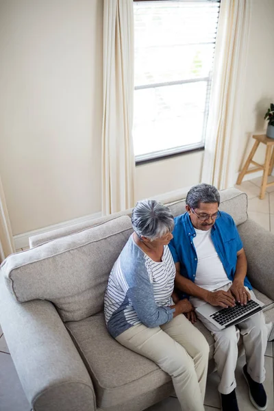 Coppia anziana che utilizza il computer portatile in soggiorno — Foto Stock