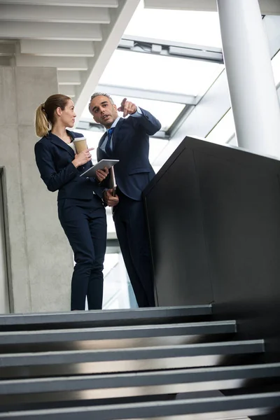 Colleghi di lavoro in piedi sulle scale e parlando — Foto Stock