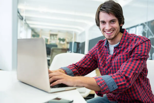 Grafisk formgivare använder laptop vid sitt skrivbord — Stockfoto