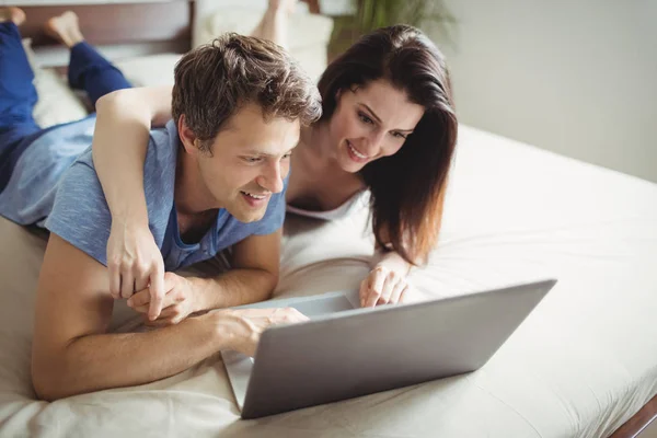 Pareja feliz usando portátil en la cama —  Fotos de Stock