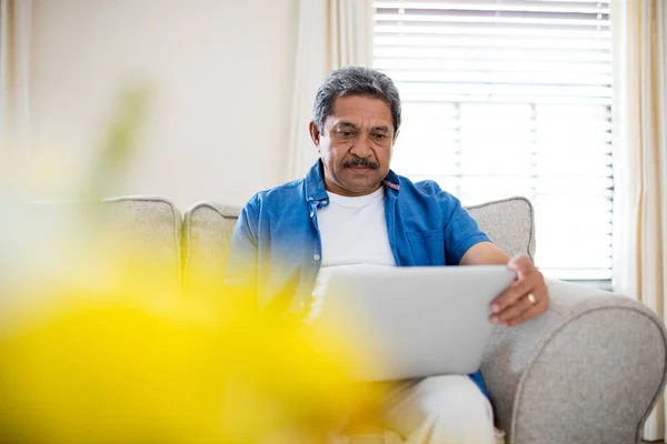 Homem sênior usando laptop na sala de estar — Fotografia de Stock