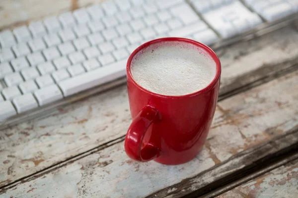 Kopje koffie naast toetsenbord op tafel — Stockfoto