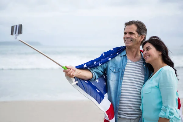 Couple enveloppé dans un drapeau américain prenant selfie — Photo