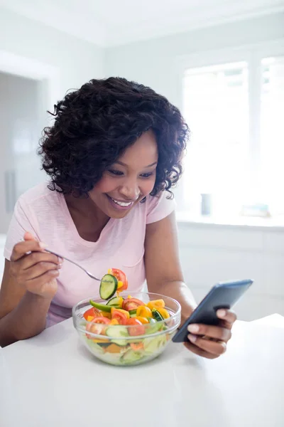 Vrouw met salade tijdens het gebruik van de telefoon — Stockfoto