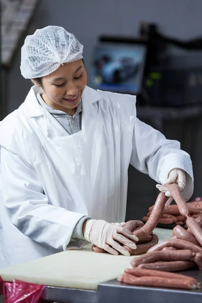 Salsichas de processamento de açougueiro feminino — Fotografia de Stock