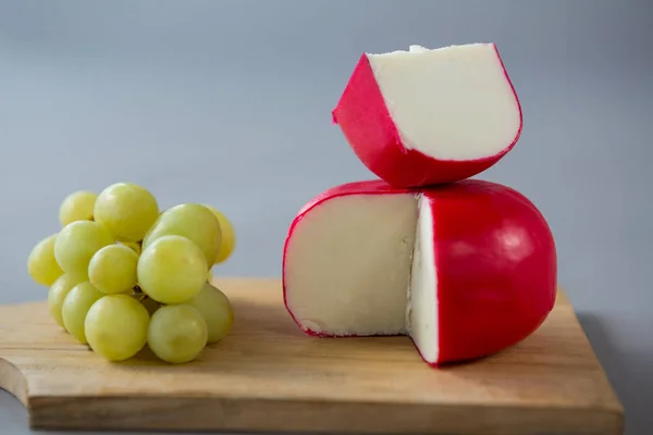 Formaggio di gouda con uva sul tagliere — Foto Stock