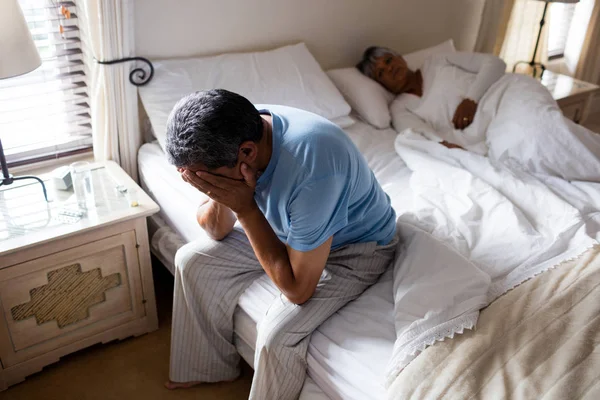 Напряженный пожилой человек, сидящий на кровати — стоковое фото