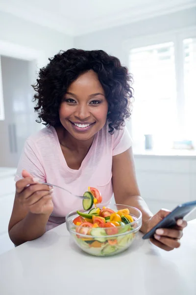 Vrouw met salade tijdens het gebruik van de telefoon — Stockfoto