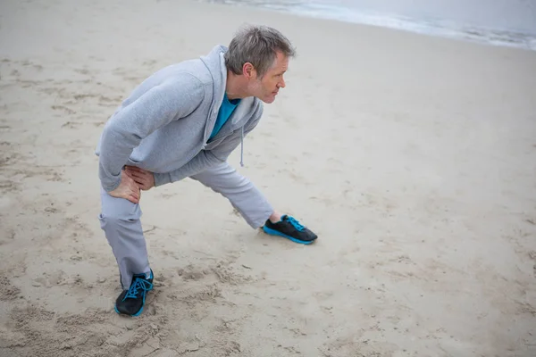 Uomo che esegue esercizio di stretching sulla spiaggia — Foto Stock