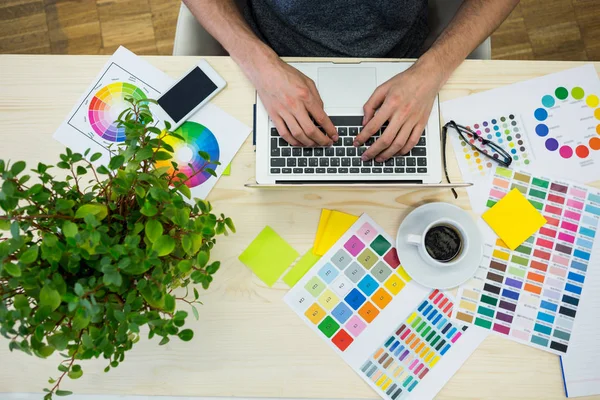 Grafisk formgivare använder laptop vid sitt skrivbord — Stockfoto