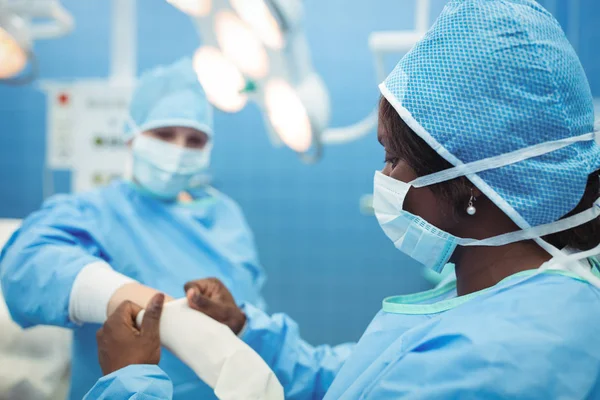 Surgeon helping her co-worker — Stock Photo, Image
