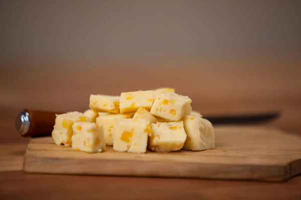 Cheese cubes on wooden chopping board — Stock Photo, Image