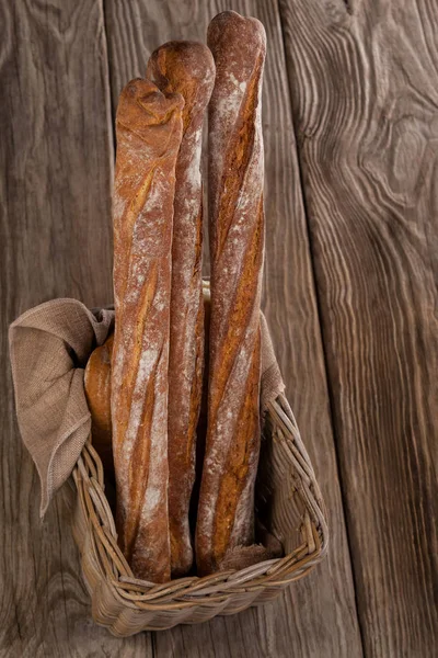 Baguetes em cesta no fundo de madeira — Fotografia de Stock