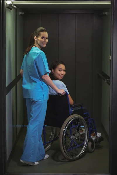 Female nurse assisting patient on wheelchair — Stock Photo, Image