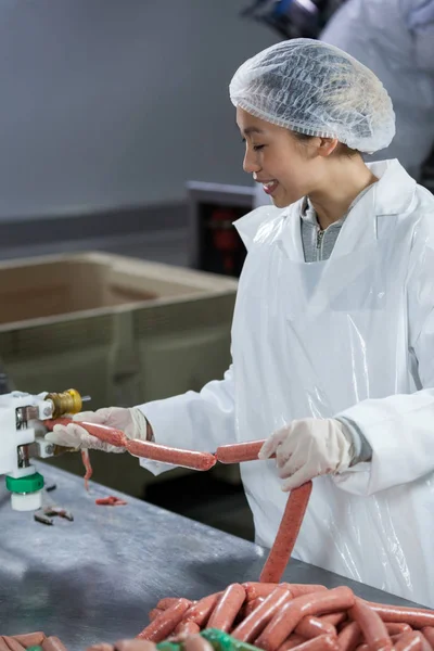 Salsichas de processamento de açougueiro feminino — Fotografia de Stock