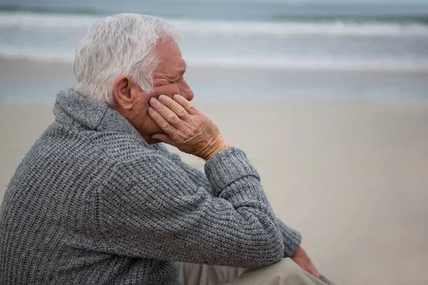 Nachdenklicher Senior sitzt am Strand — Stockfoto