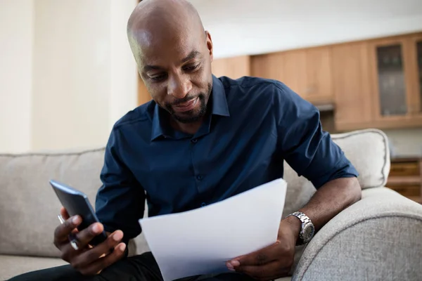 Man looking at document while using phone — Stock Photo, Image