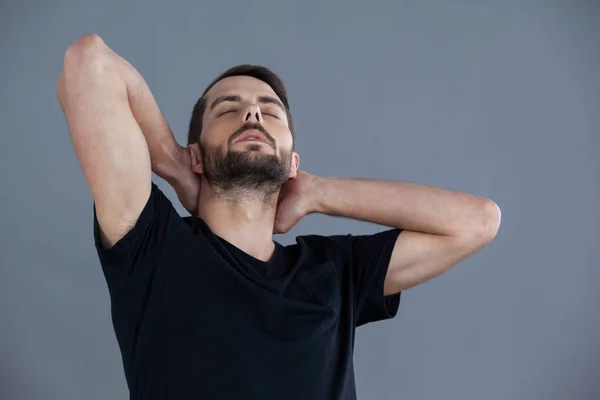Hombre en camiseta negra con las manos detrás del cuello —  Fotos de Stock