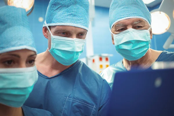 Surgeons discussing over clipboard in operation theater — Stock Photo, Image