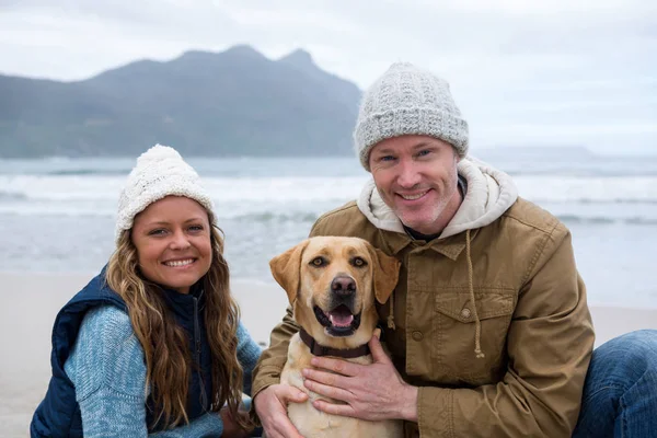 Casal com cão de estimação na praia — Fotografia de Stock