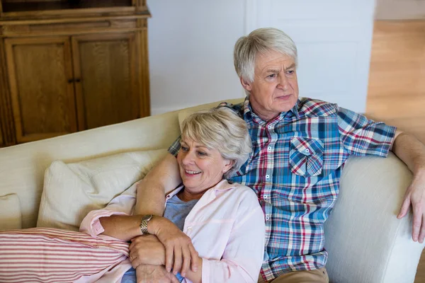 Улыбающаяся пожилая пара отдыхает на диване — стоковое фото