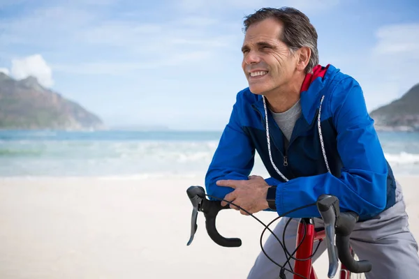 Hombre sonriente apoyado en la bicicleta — Foto de Stock