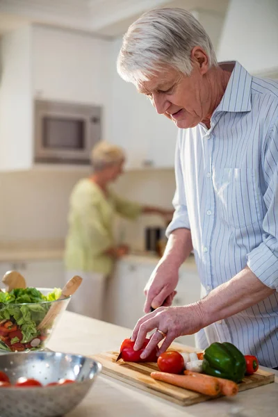 Senior man cutting vegetables for salad — Stock Photo, Image