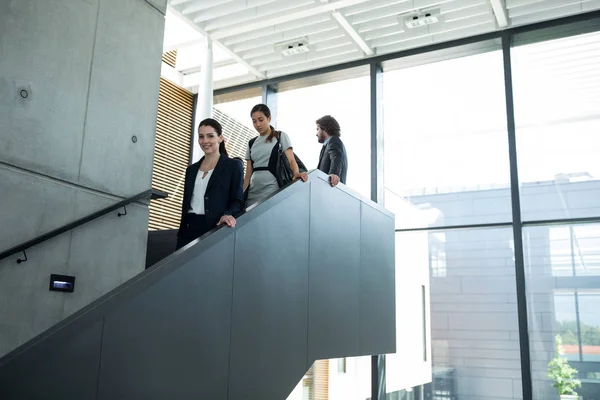 Businesswoman with colleagues climbing down stairs — Stock Photo, Image