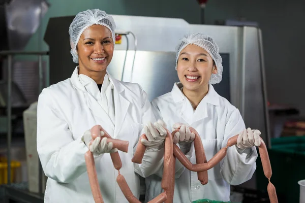 Female butchers processing sausages — Stock Photo, Image