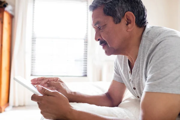 Senior man använder digital tablett på säng — Stockfoto