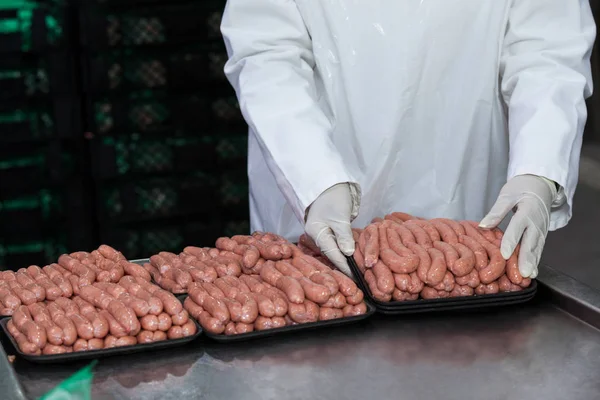 Butcher packing raw sausages — Stock Photo, Image