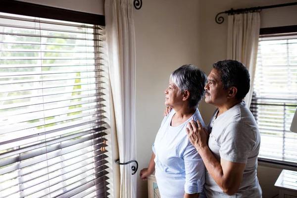 Äldre par tittar genom fönstret — Stockfoto