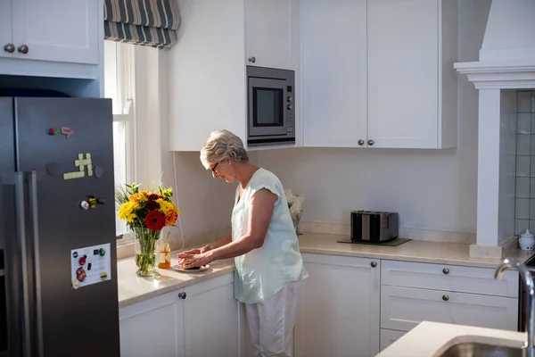 Starší žena připravuje snídani v kuchyni — Stock fotografie