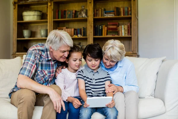 Barnbarn med tablett med sina morföräldrar — Stockfoto