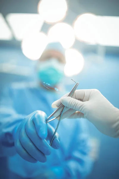 Хирург передаёт хирургический инструмент коллеге — стоковое фото