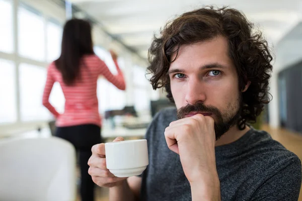 Male graphic designer holding coffee cup at desk — Stock Photo, Image