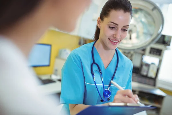 Female nurse writing on clipboard — Stock Photo, Image