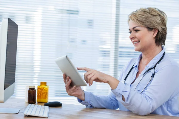 Médico sentado na mesa e usando tablet — Fotografia de Stock