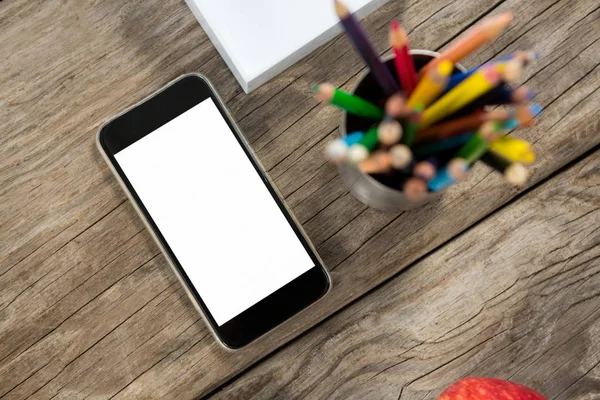 Smartphone i kolor kredki na drewnianym stole — Zdjęcie stockowe