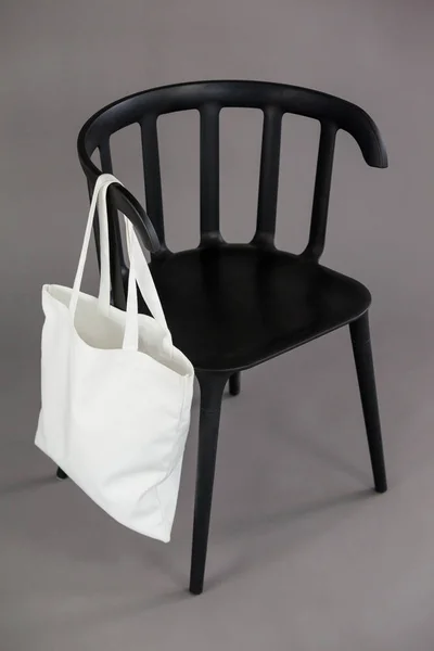 Witte boodschappentas opknoping op zwarte stoel — Stockfoto