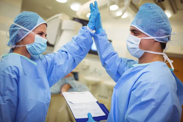 Mannelijke en vrouwelijke chirurg high-five geven aan elkaar — Stockfoto