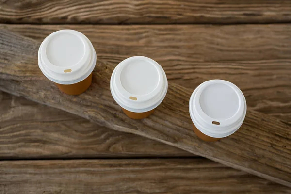 Disposable coffee cups on wooden plank — Stock Photo, Image