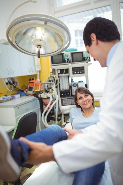Médico examinando uma perna pacientes do sexo feminino — Fotografia de Stock