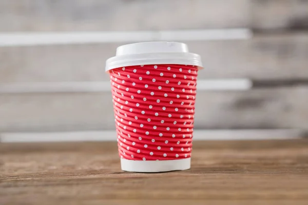 Disposable coffee cup with polka dots on wooden table — Stock Photo, Image