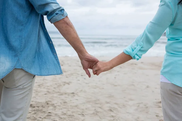 Пара тримає руки на пляжі — стокове фото