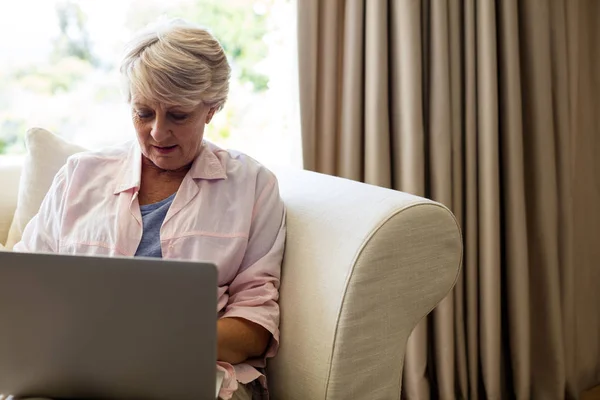 Mujer mayor usando portátil en la sala de estar — Foto de Stock