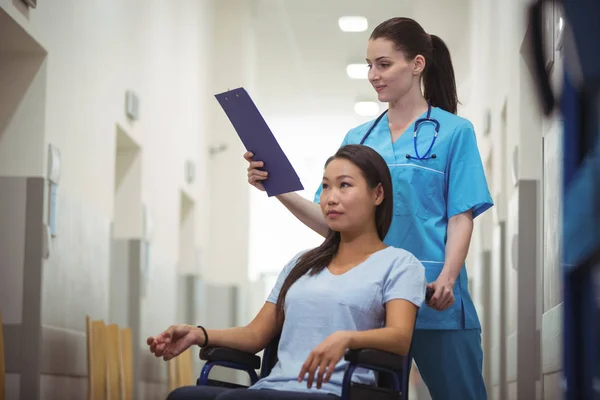 Female nurse assisting patient on wheelchair — Stock Photo, Image