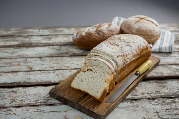 Pan con cuchillo en tabla de cortar —  Fotos de Stock