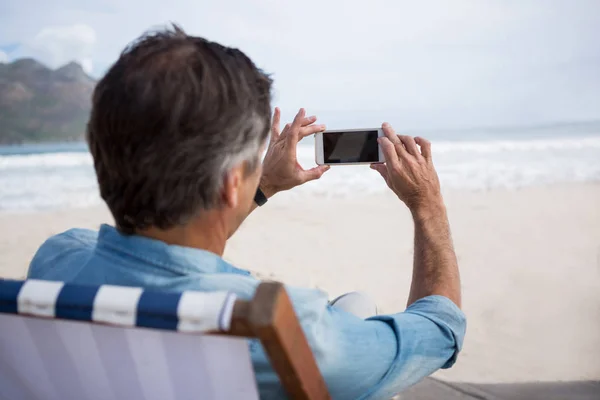 Homme prenant des photos au téléphone à la plage — Photo