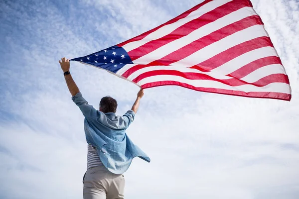 Man håller amerikanska flaggan på stranden — Stockfoto